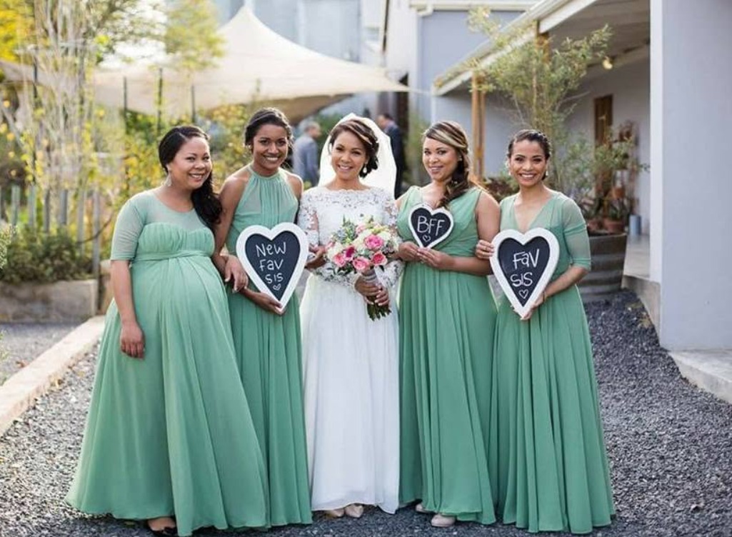 Bride and bridesmaids in sage green dresses holding fresh bouquets
