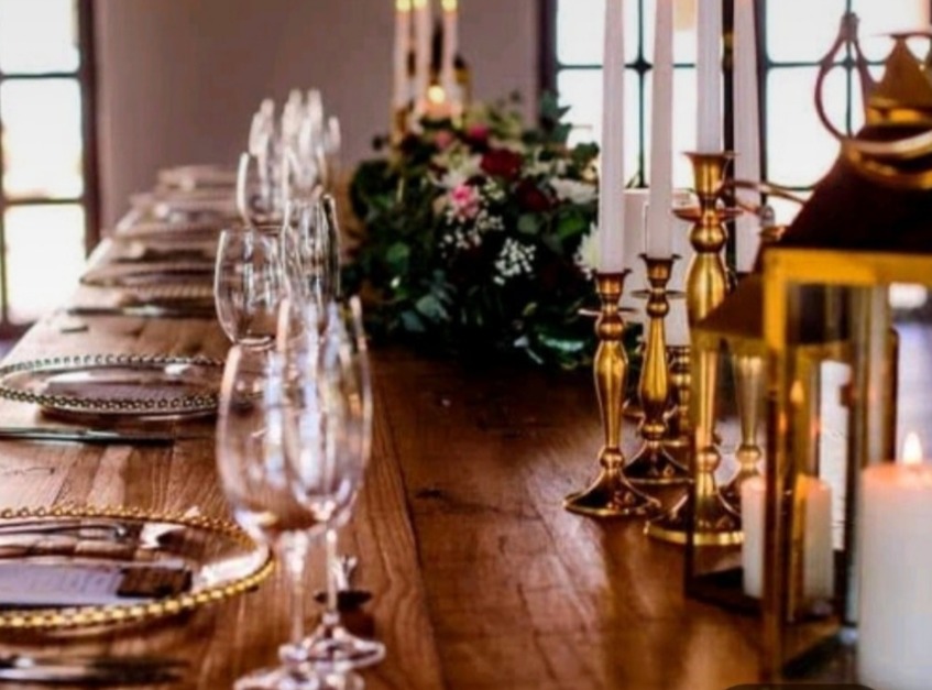 Reception table with gold candleholders, glassware and fresh florals