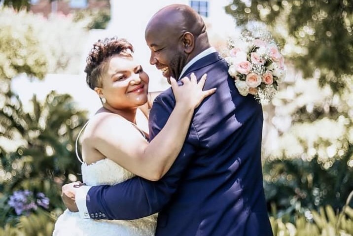 Bride and groom laughing in a warm embrace in a garden