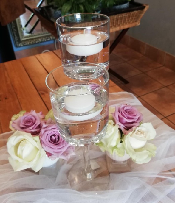 Glass floating-candle centrepiece surrounded by roses