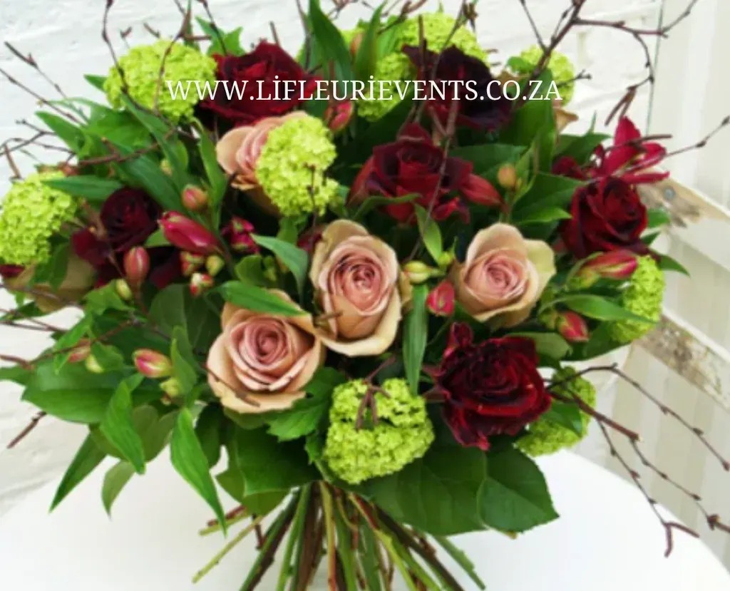 Bouquet of burgundy and blush roses with green blooms and leafy branches