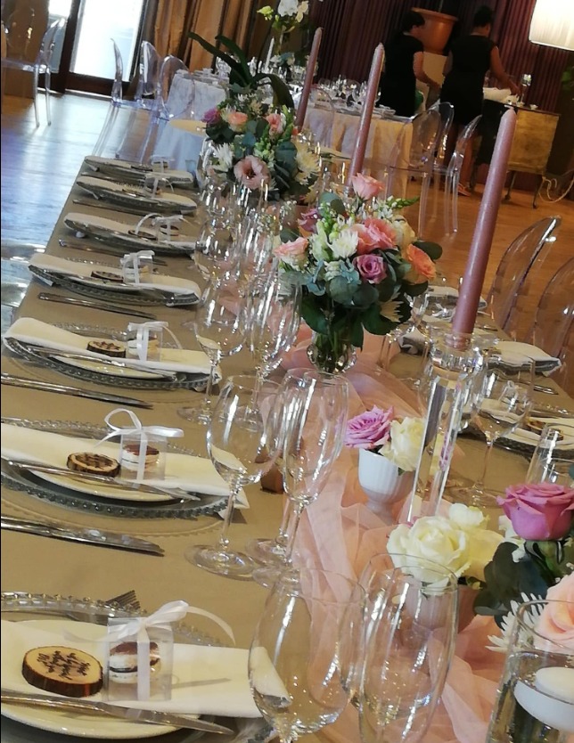 Long reception table with floral arrangements, candles and place settings