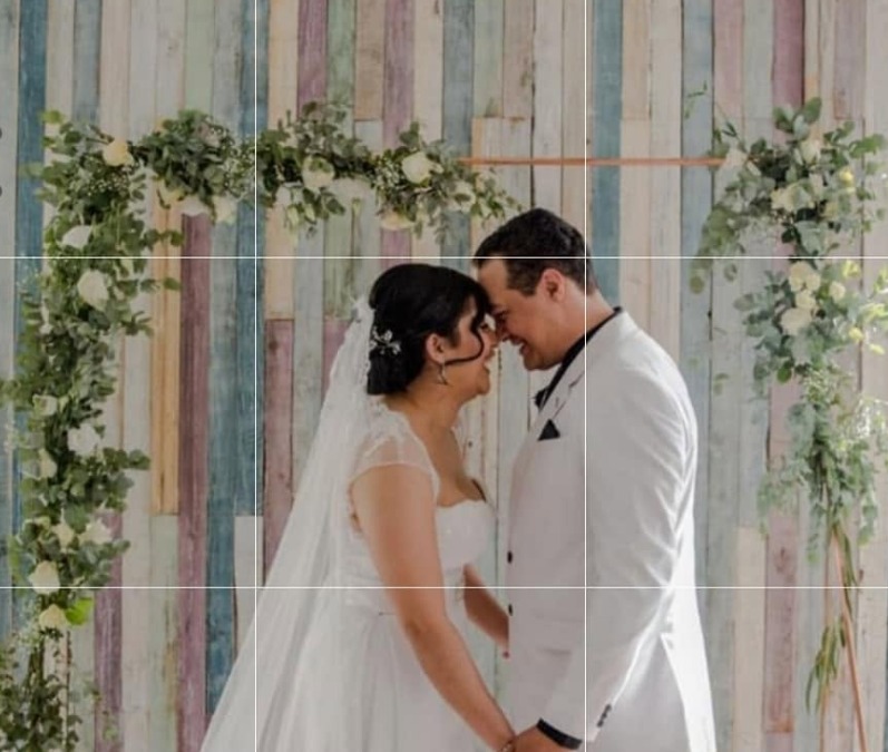 Wedding couple beneath a floral arch, styled with greenery and draped fabric