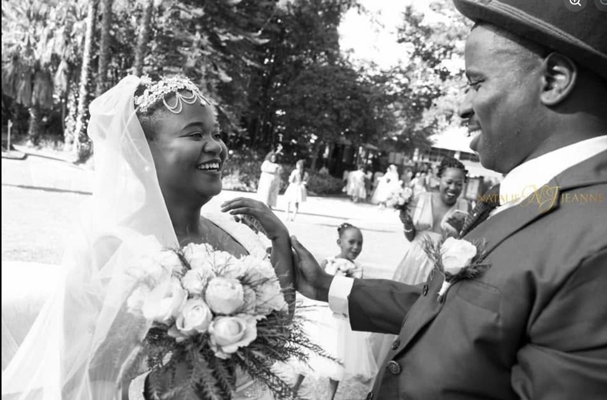 Black and white photo of a bride holding a rose bouquet beside the groom