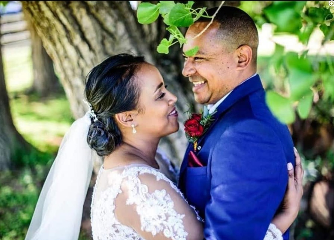 Newly married couple celebrating together beneath a leafy tree